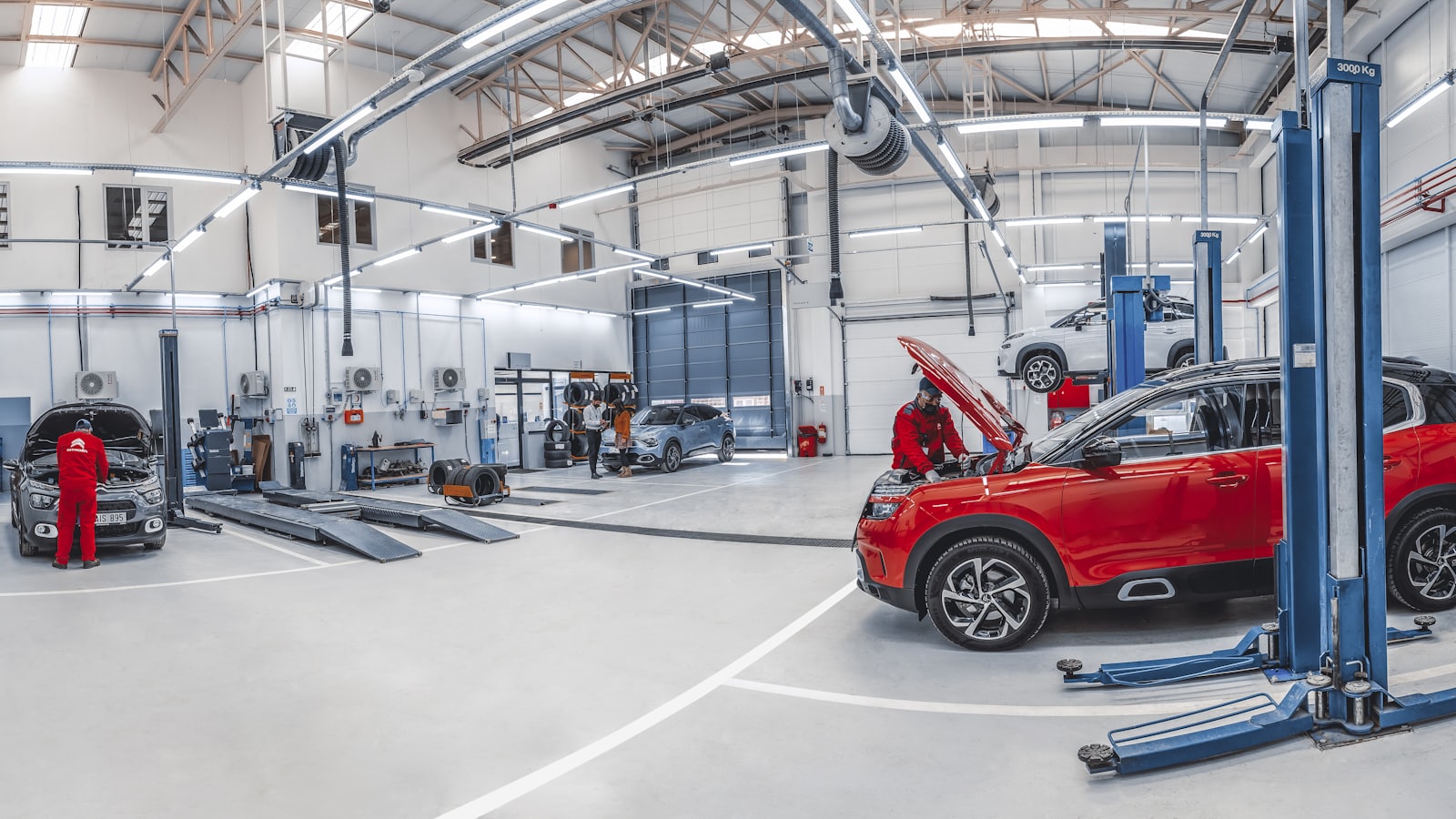 Cars being serviced on ramps inside a busy modern car workshop